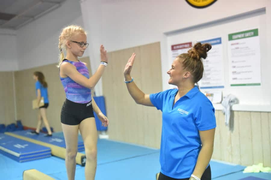 Coach high-fiving young girl standing on beam