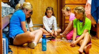 woman teaching girls how to make bracelets