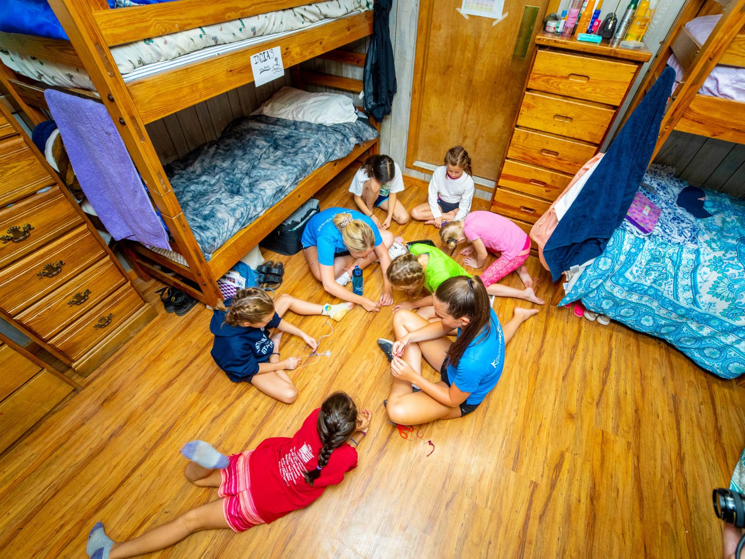 campers and counselors sitting in a circle on the floor of a cabin