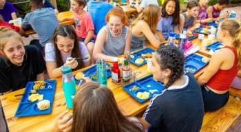children laughing and eating at picnic tables
