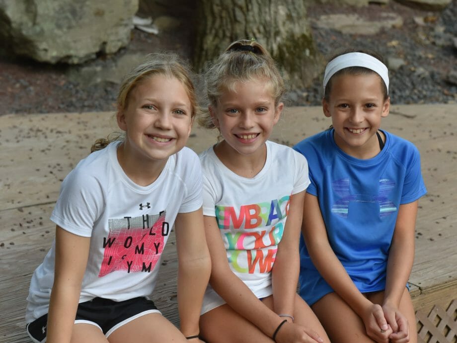 three girls sitting and posing for a group photo