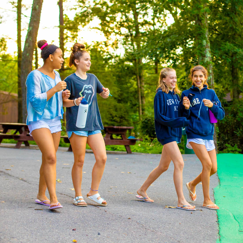 four campers walking across the grounds laughing