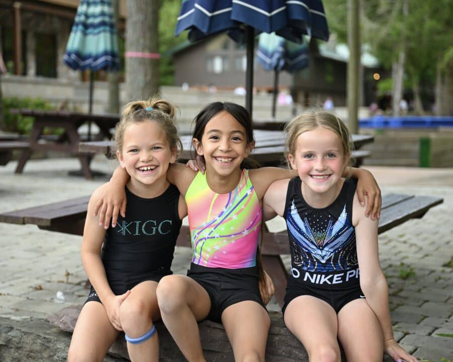 Three girl campers pose for a photo wearing gymnastics attire.