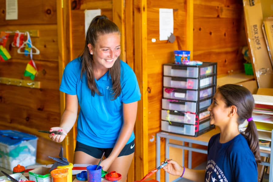female staff member laughing with camper while doing crafts