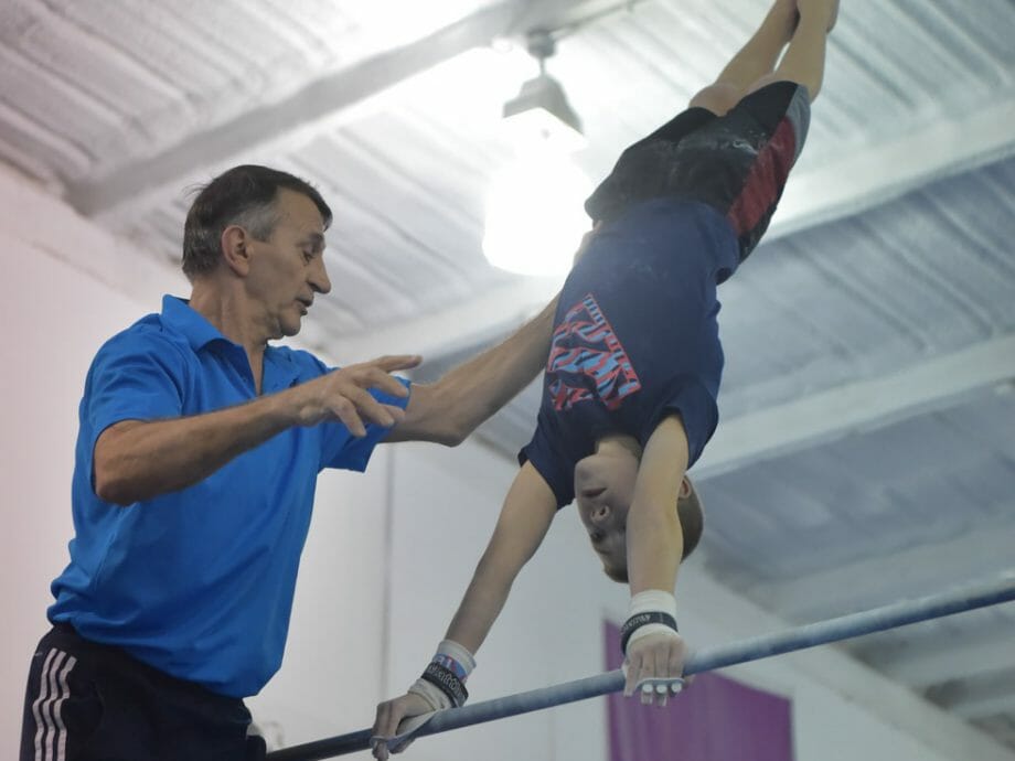 boy being instructed on the high bar