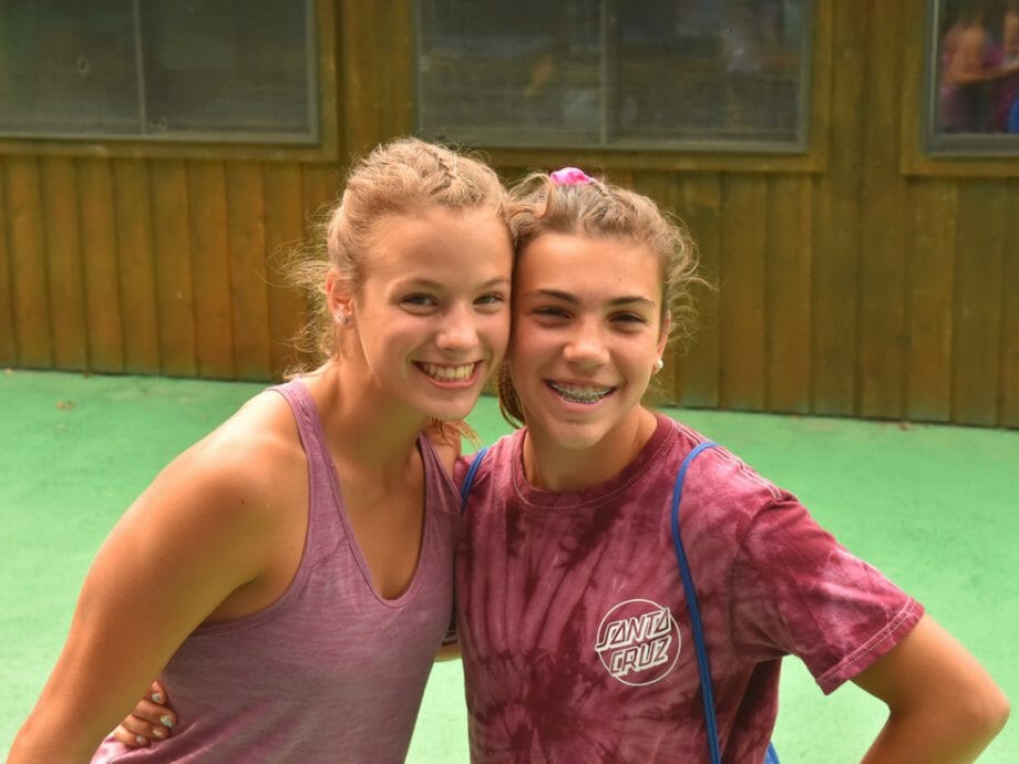 two girls posing for a photo together outside