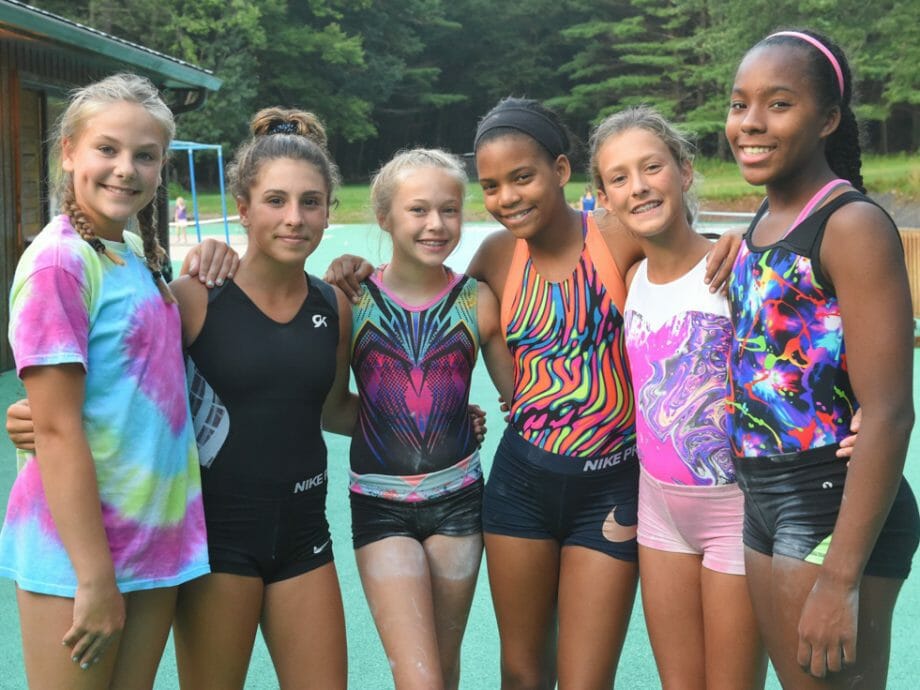 girls posing for a group photo outside on the tennis courts