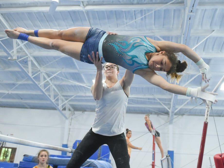 camper being instructed on uneven bars dismount