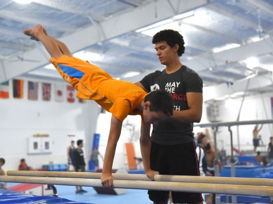 boy being instructed on the parallel bars
